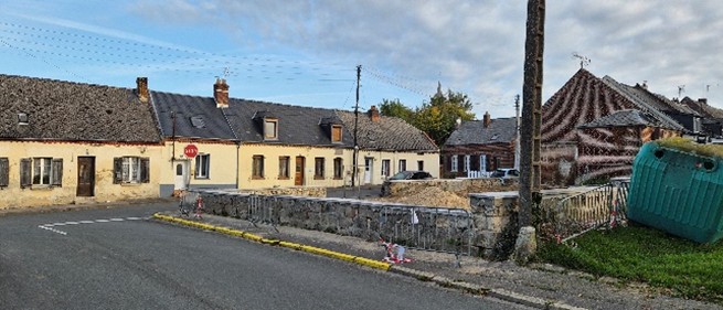 A street with houses and a stone wall AI-generated content may be incorrect.